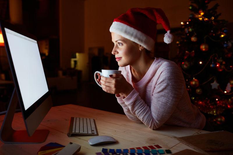 捧着杯子看着电脑屏幕的圣诞女孩