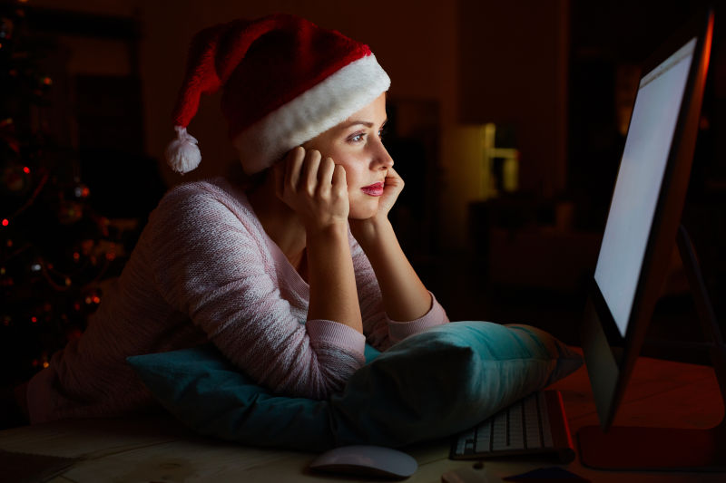 戴着圣诞帽的女孩看着电脑屏幕