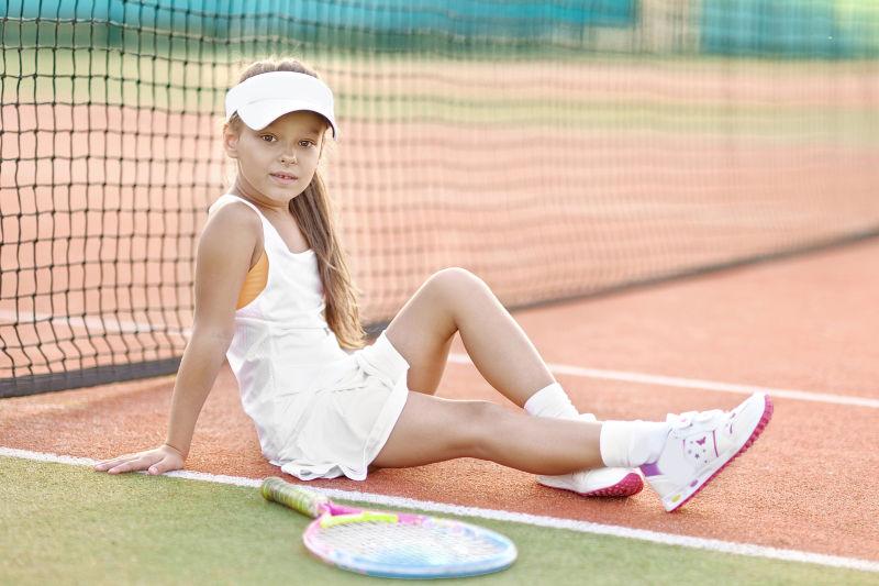 网球场上坐在地上的一个小女孩