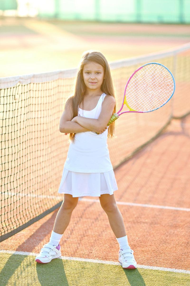 网球场上拿着网球拍的小女孩