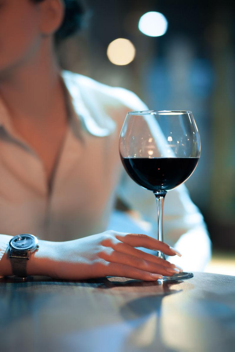 酒吧里坐在吧台边拿着红酒杯的女人