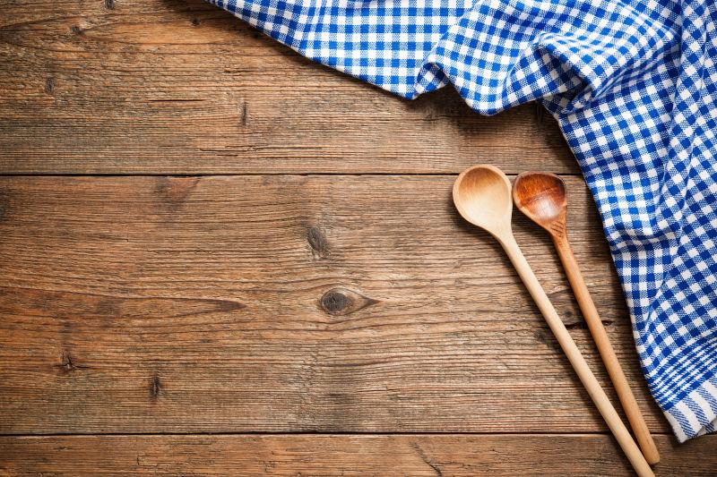 木桌上的蓝色格子餐布和两个木质勺子