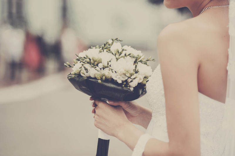 街上拿着新娘花束的美丽新娘