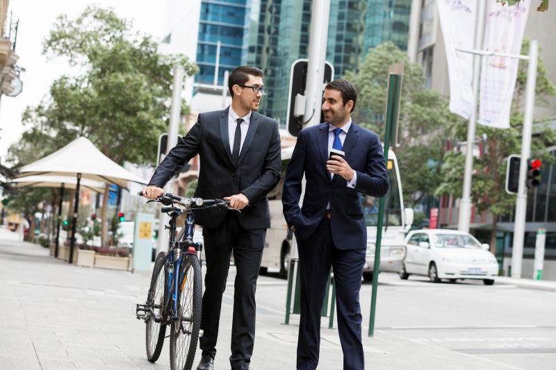 城市街头推着自行车交谈的两个年轻的商人