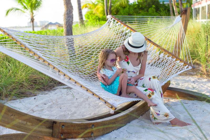 母亲和女儿在热带异国风情度假村的吊床上放松