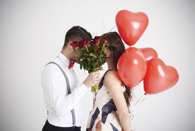 一对外国情侣拿着玫瑰花和红色气球