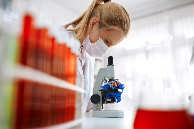 实验室里使用显微镜进行化学分析的女研究员