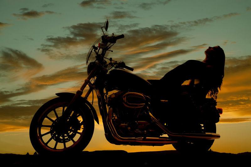 黄昏背景中骑在摩托车上的女人