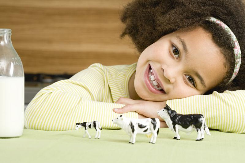 女孩趴在放着牛奶和奶牛玩具的桌子上
