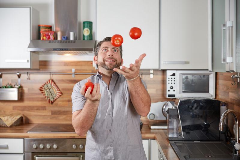 男子在厨房用番茄表演杂耍