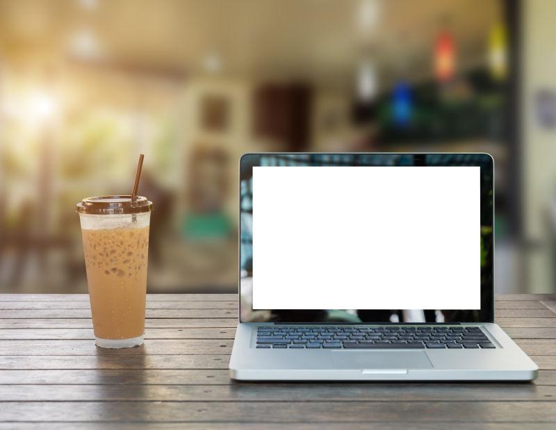 木桌上的冰咖啡和笔记本电脑