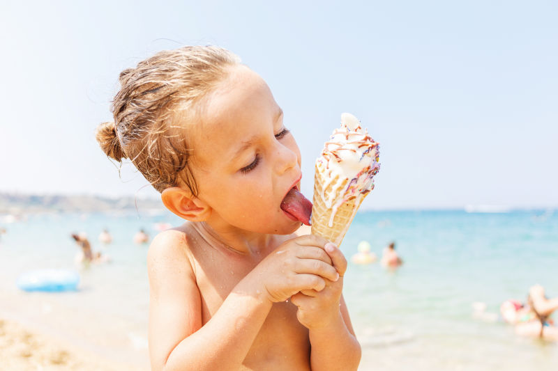 沙滩上开心吃冰淇淋的金发男孩