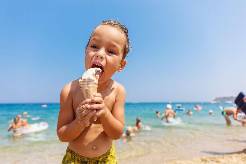 金发男孩正在海滩上吃冰淇淋