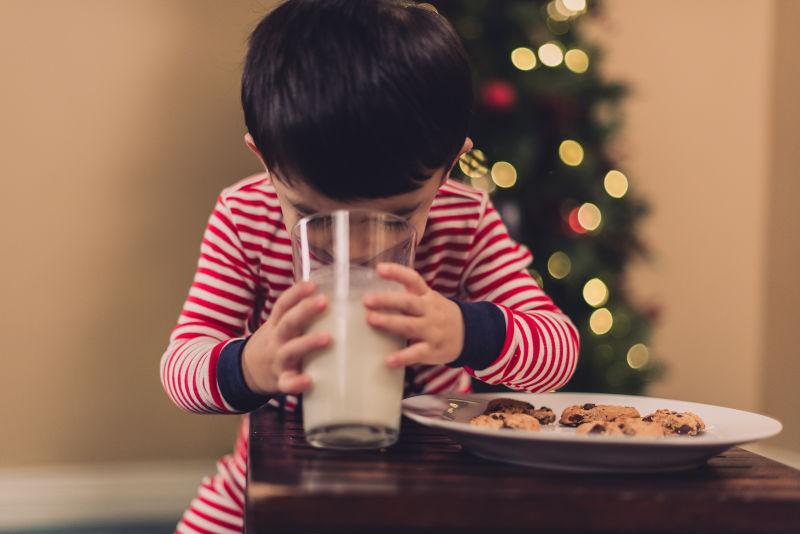 圣诞树下的小男孩在喝牛奶