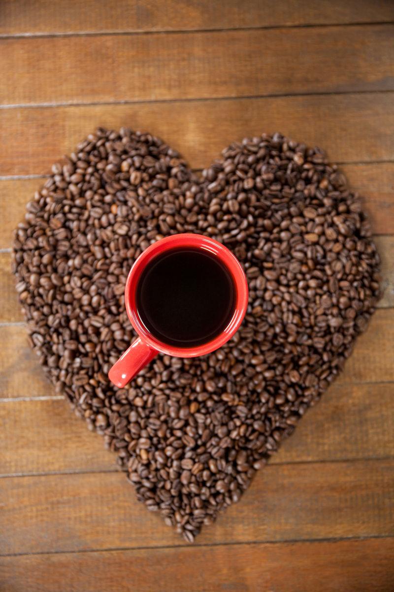 木制咖啡桌上有心形咖啡豆与红色咖啡