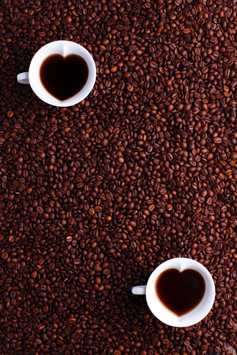 两杯爱心咖啡在咖啡豆背景上