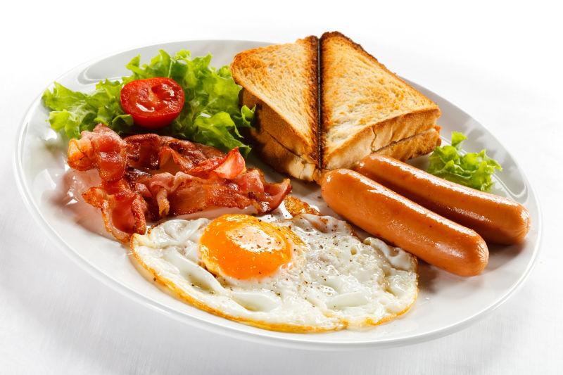 白色背景下放在白色餐盘里的鸡蛋火腿面包早餐