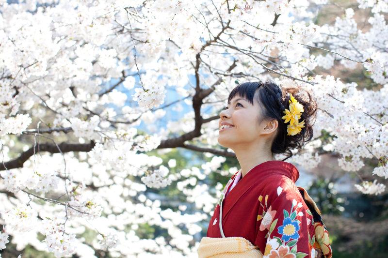 白色樱花树下微笑的日本和服女人