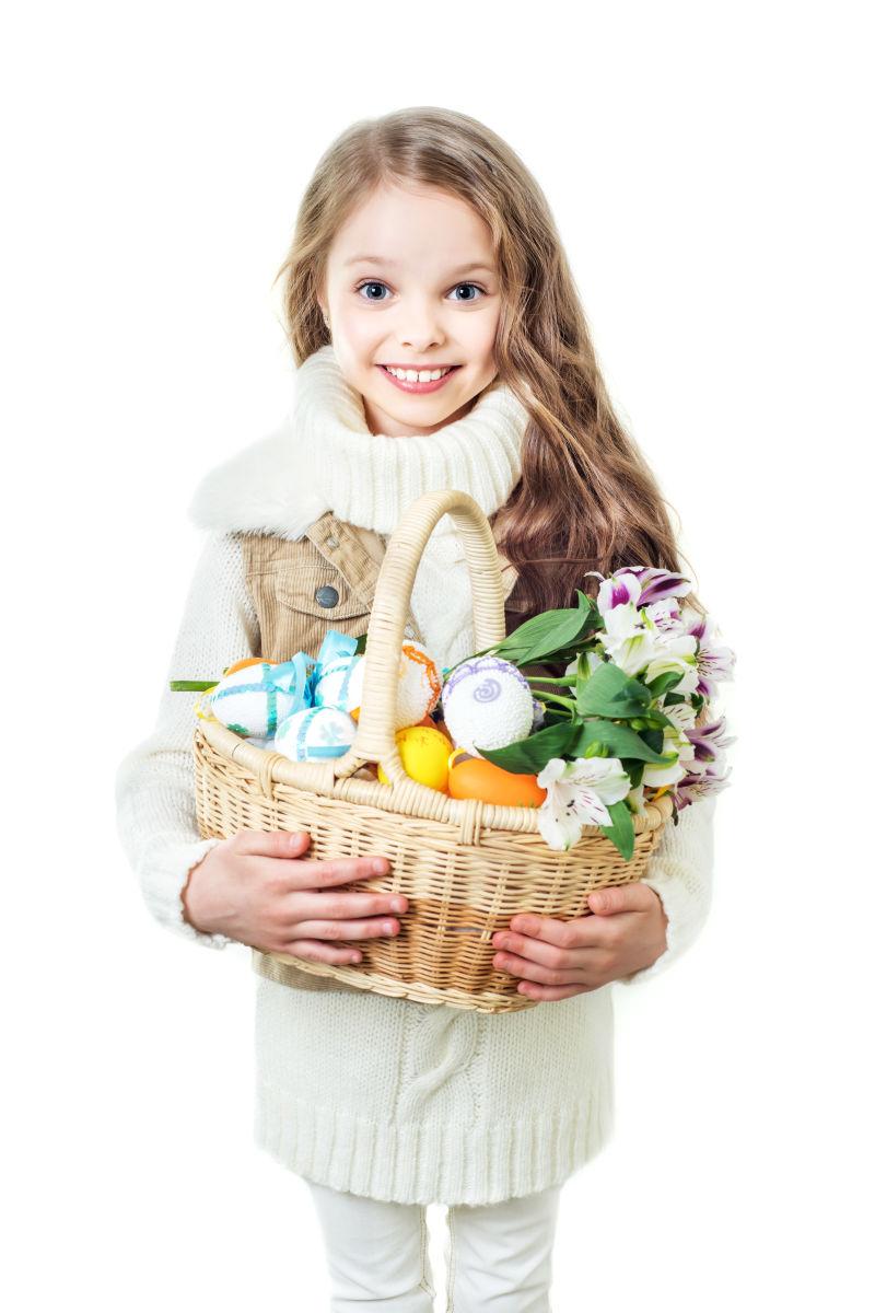 白色背景下可爱的小女孩抱着装满复活节彩蛋的篮子