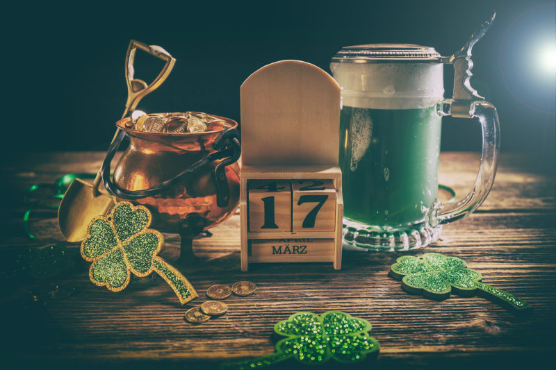 木桌上的绿色啤酒和装着金币的金罐子还有美丽的四叶草饰品