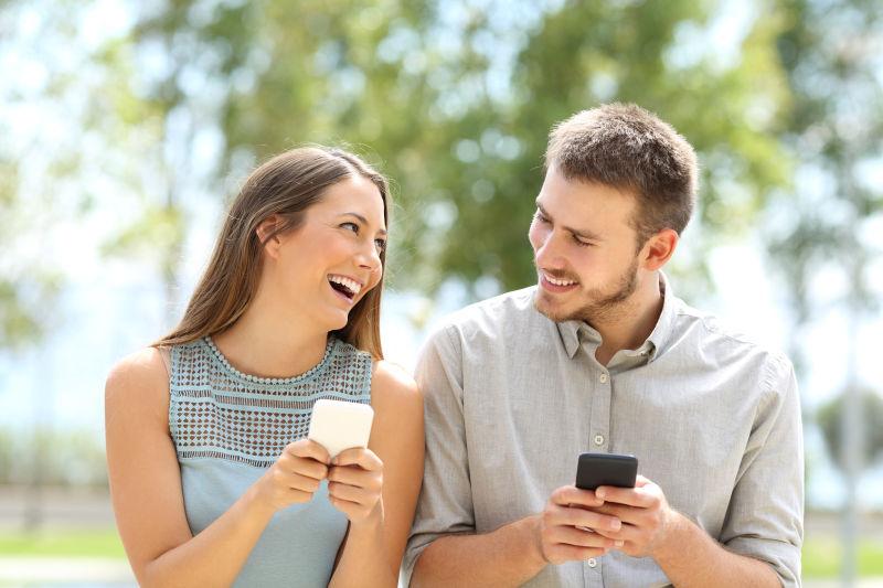 一对情侣在公园户外玩和使用智能手机