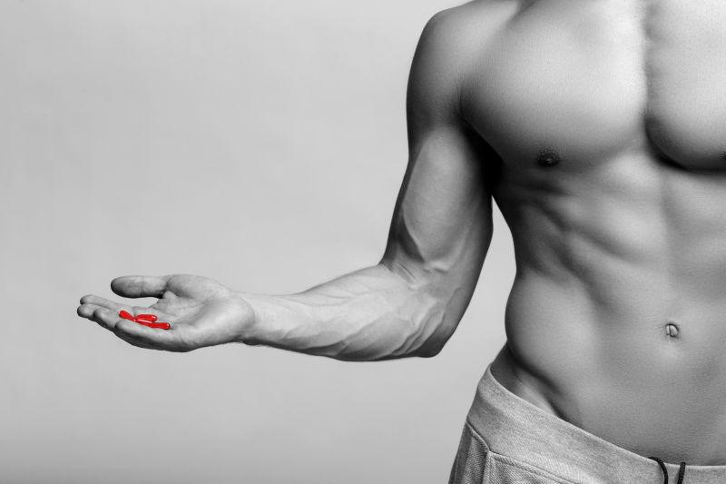 肌肉发达的男人手里拿着红色药物
