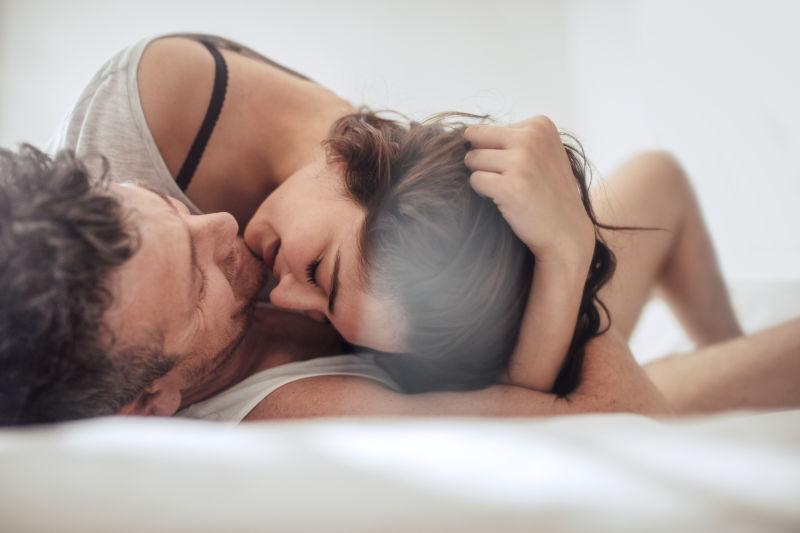 年轻夫妇在床上一起抚摸亲吻