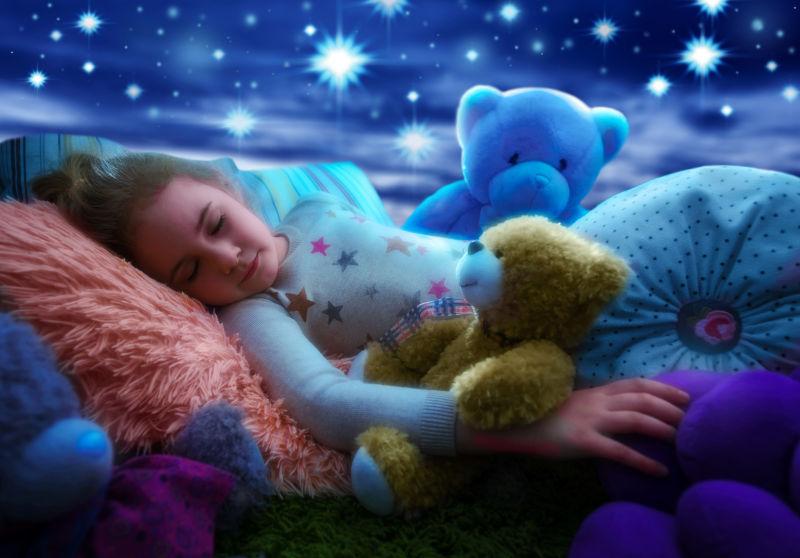 小女孩搂着泰迪熊在床上睡觉