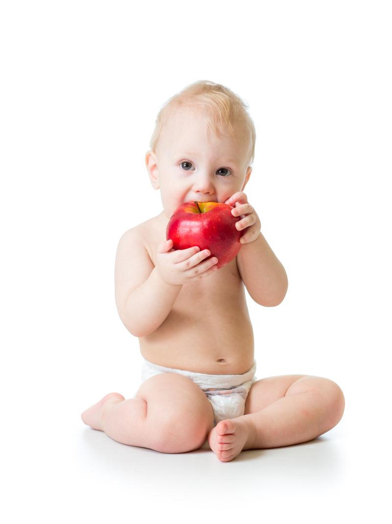 白色背景下吃红苹果的男婴
