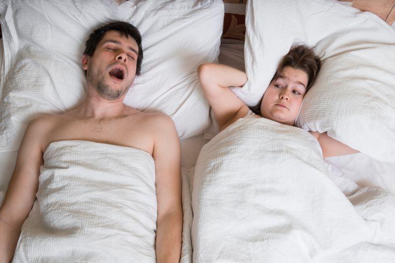 睡觉时打鼾的丈夫和抱着枕头的妻子