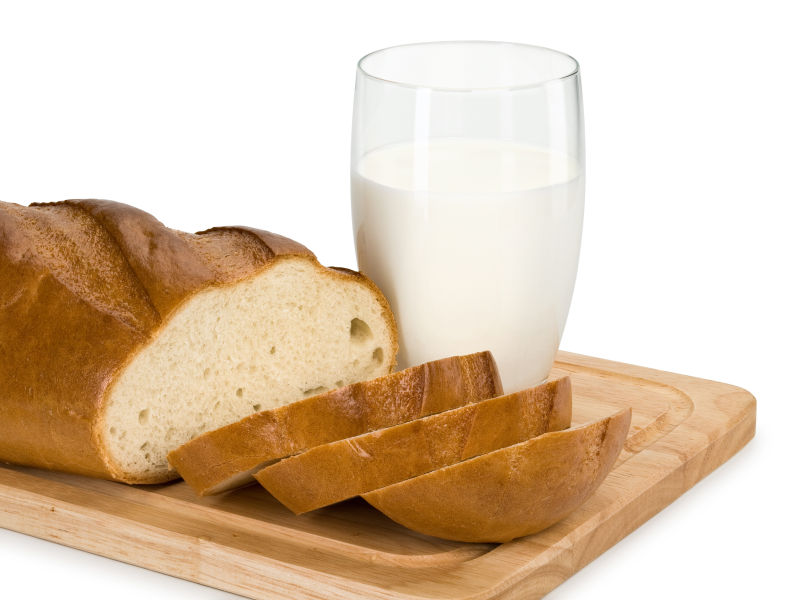 白色背景前木质板上的牛奶和面包