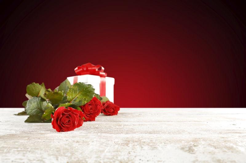 白色桌面上红色玫瑰花与礼品盒