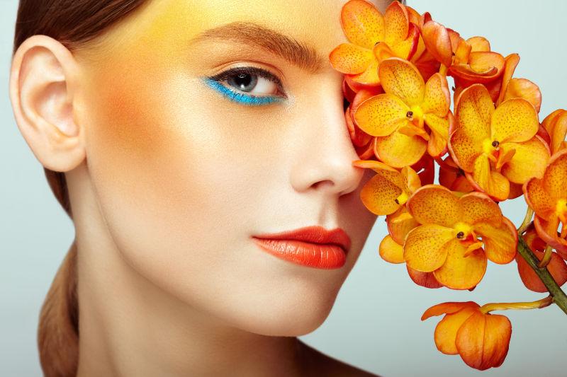 化妆橙色的美女拿着橙色的兰花