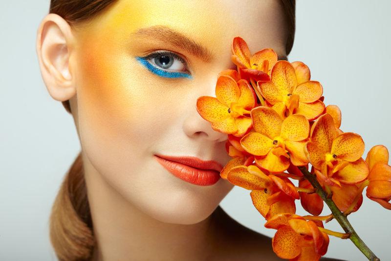 化妆橙色眼影的女子拿着兰花