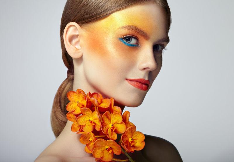 化妆眼影的美女和橙色兰花