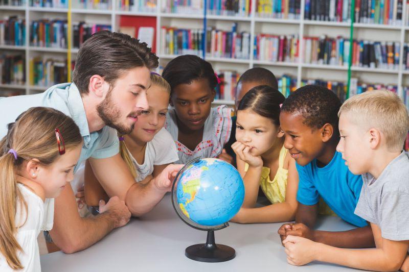 小学生和教师在图书馆看地球