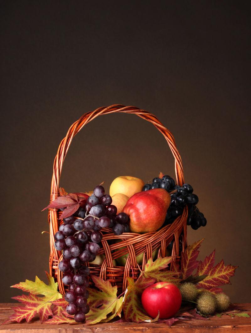 棕色背景下的篮子里的葡萄和苹果