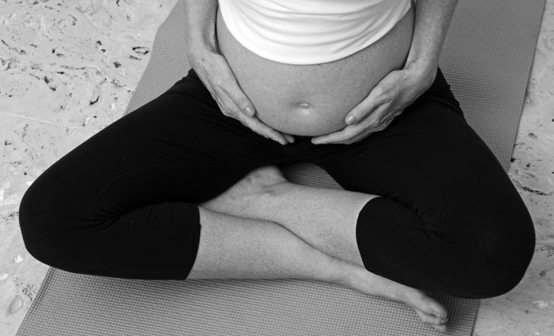 孕妇一边做腹部瑜伽一边抱着肚子