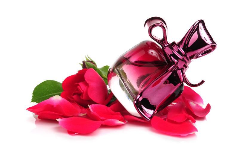 白色背景下红色玫瑰花瓣衬托下的香水瓶