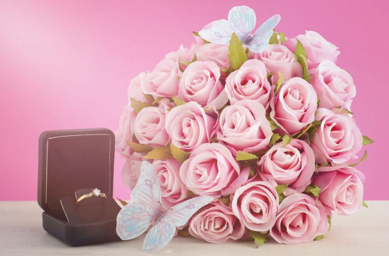美丽的一束粉色玫瑰花和放在盒子里的结婚戒指