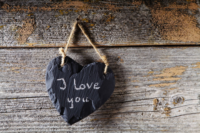 黑色的爱心挂在木板墙上