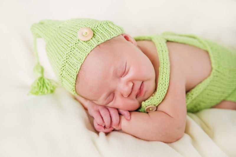 新生婴儿戴着编织的绿色帽子在睡觉