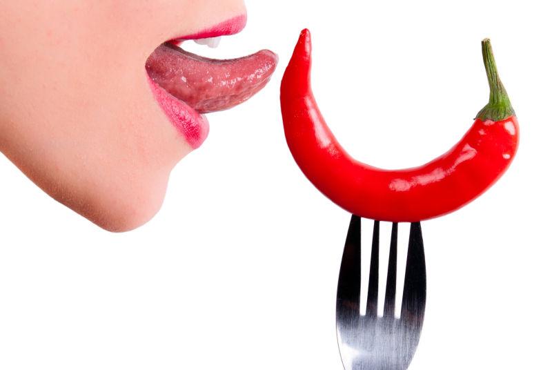 美女的舌头与叉子上的辣椒
