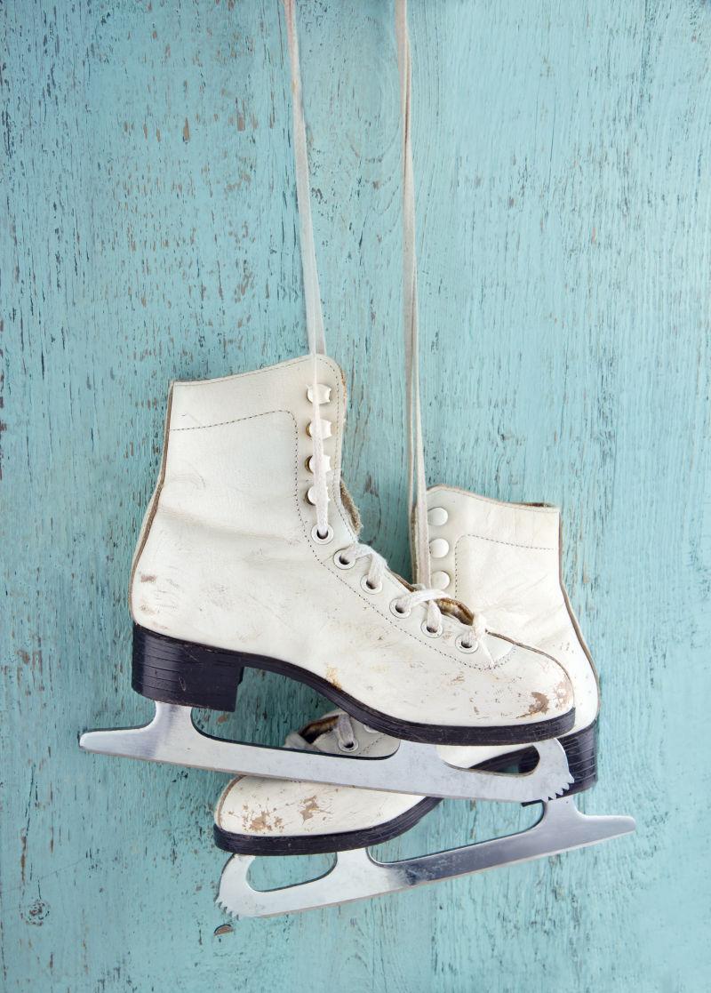 淡蓝色背景下有着长长的鞋带的白色一双溜冰鞋