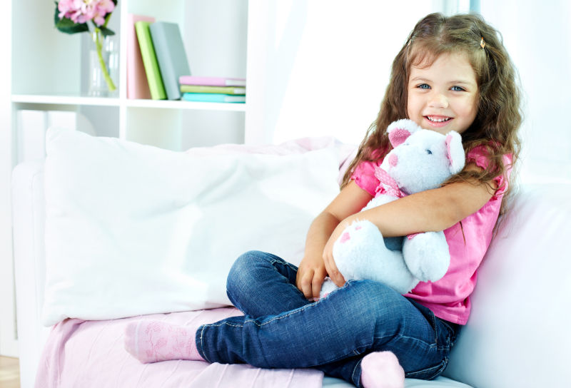 坐在沙发上抱着玩具的小女孩