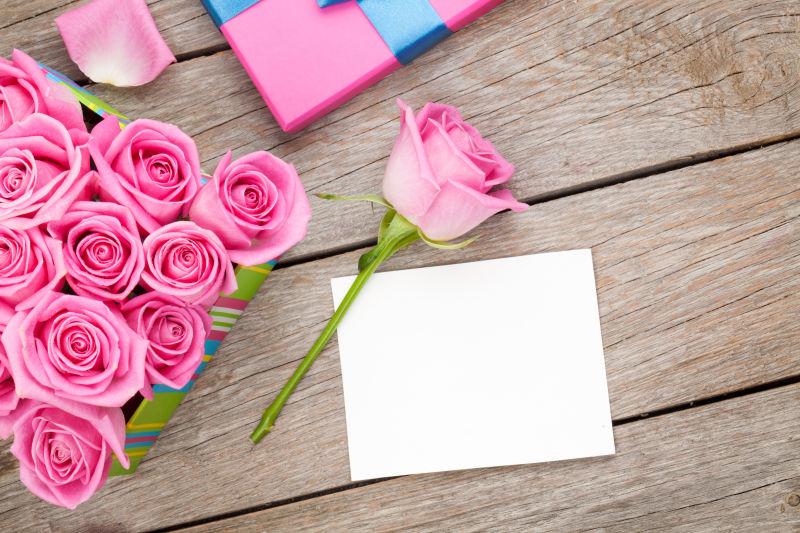情人节贺卡和满满的粉红色玫瑰在木桌上