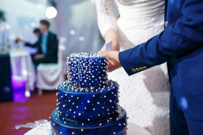 新郎新娘一起切蓝色结婚蛋糕