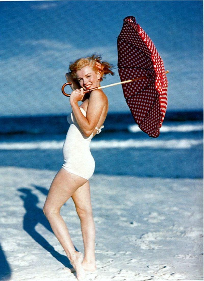 拿着伞的美女在海滩边行走