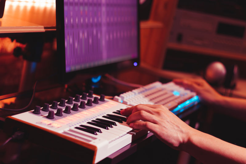 音乐家在数字音箱中用手弹奏MIDI键盘合成器在电脑上录制音乐