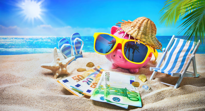 带着太阳镜的小猪存钱罐在海滩度假时放松-旅游省钱理念-暑假